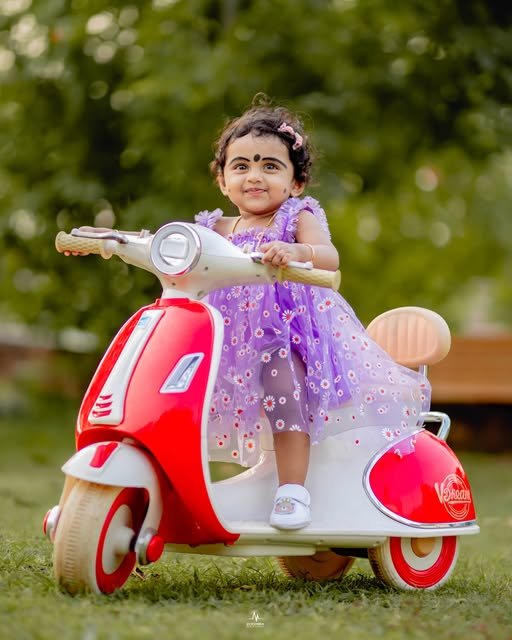 Child on a red toy scooter, pre-birthday photoshoot